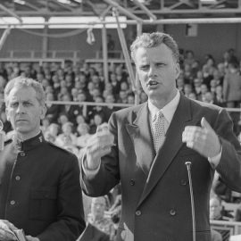 Billy Graham preaching to a crowd.
