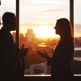 A manager and employee talking in front of a sunset and a window, showing how to make employees feel valued.