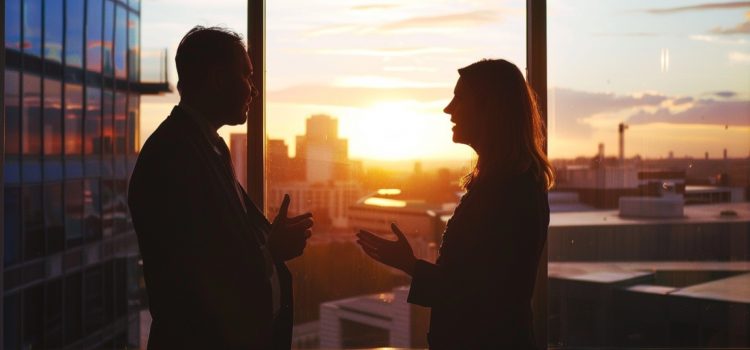A manager and employee talking in front of a sunset and a window, showing how to make employees feel valued.
