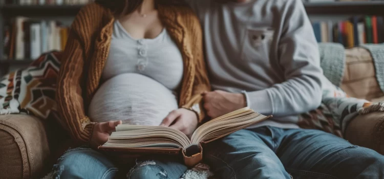 A pregnant woman and her husband reading a book on the couch.