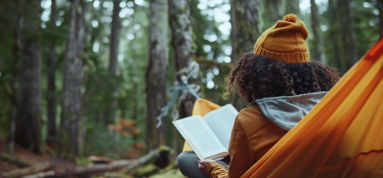 A girl reading a book while in a hammock in the forest