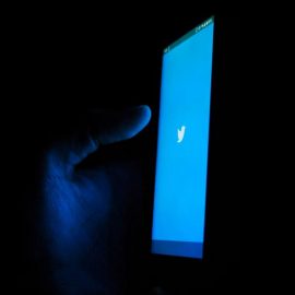 A phone in a dark room with the Twitter logo on it