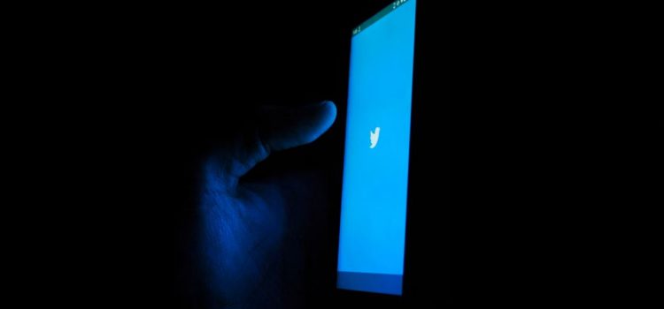 A phone in a dark room with the Twitter logo on it