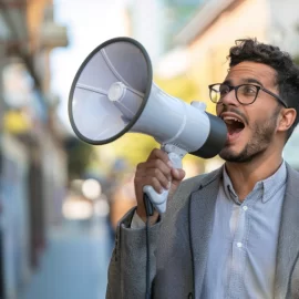 a young man wearing glasses speaking into a megaphone on a city street illustrates how to get customers for a new business