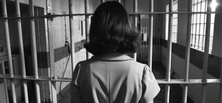 a brunette woman from behind standing in a prison cell in the late 1960s