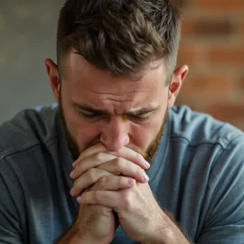 a bearded man praying with his head bowed and his hands clasped illustrates a belief that God will see you through