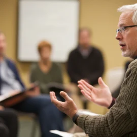 a white-haired man talking to a small group of listeners illustrates Robert Cialdini's authority principle of influence