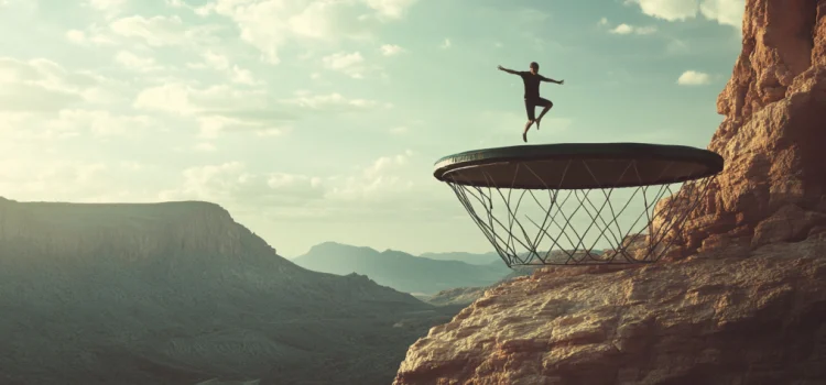 a man jumping on a trampoline on a mountain cliff illustrates the causes of human error