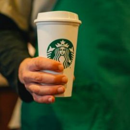 A Starbucks employee holding a coffee cup as part of the Starbucks management strategy