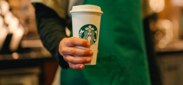 A Starbucks employee holding a coffee cup as part of the Starbucks management strategy