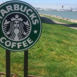 A Starbucks sign in front of grass, representing Starbucks's social responsibility