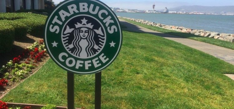 A Starbucks sign in front of grass, representing Starbucks's social responsibility