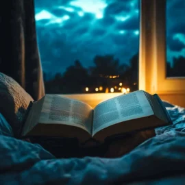 An open book on a bed looking out a window at night