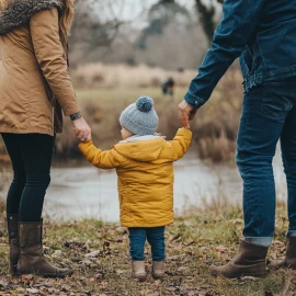 Parents holding their child outside in the fal, knowing how to raise good kids