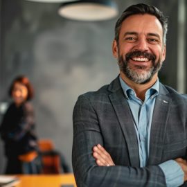 A smiling man at work with coworkers behind him illustrates a career that makes a difference