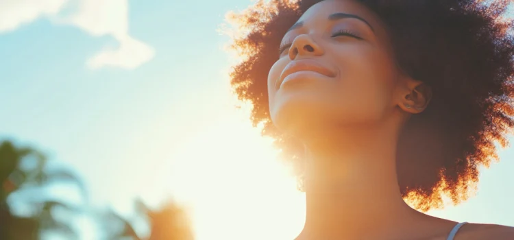 A woman feeling sunlight hormones with her eyes closed outside