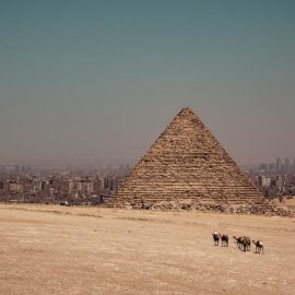 An ancient pyramid in Egypt with modern cities in the distance illustrates the rise and fall of empires