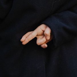 A woman's hands crossing her fingers behind her back, hoping luck does exist