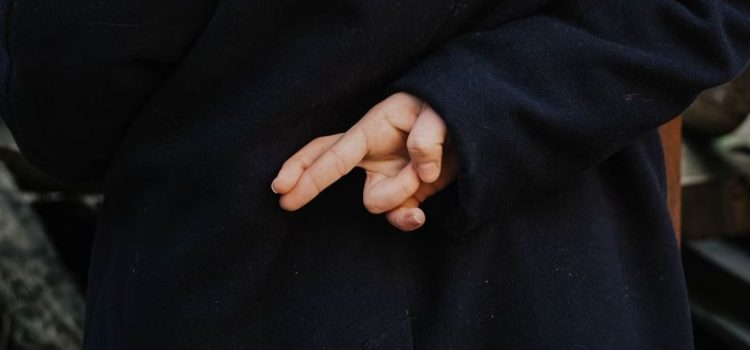 A woman's hands crossing her fingers behind her back, hoping luck does exist