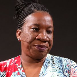 Activist Tarana Burke giving a speech in front of a black background