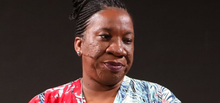 Activist Tarana Burke giving a speech in front of a black background