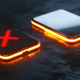 Two cellphones sitting on a desk, one of them with a red X on it, showing the double-edged sword of technology