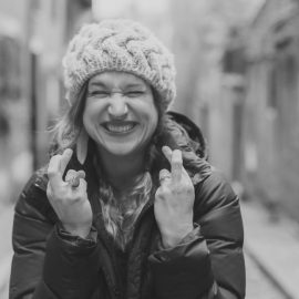 A black and white image of a woman crossing the finders on both hands because she's trying to be lucky