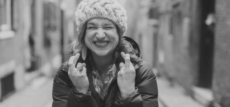 A black and white image of a woman crossing the finders on both hands because she's trying to be lucky