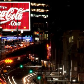 A lighted Coca-Cola ad in a city at nighttime illustrates the importance of a consistent brand image