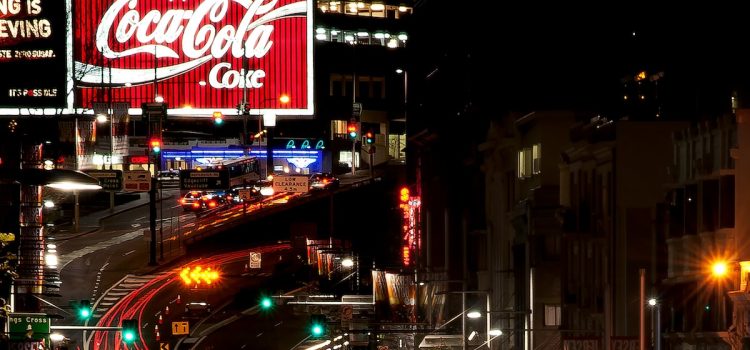 A lighted Coca-Cola ad in a city at nighttime illustrates the importance of a consistent brand image