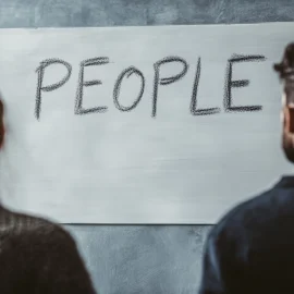 A man and woman looking at a whiteboard that reads "PEOPLE" to learn how to understand people better