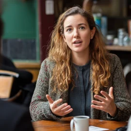 A woman who knows how to engage people, talking to them at a coffee shop