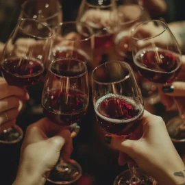 A group of hands toasting with glasses of red wine at Christmas while having a peaceful holiday celebration