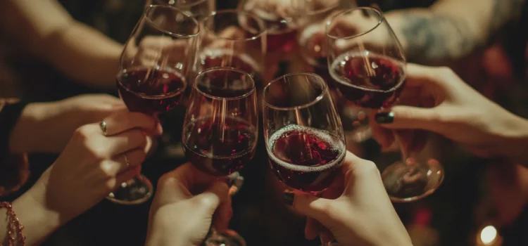 Un grupo de manos brindando con copas de vino tinto en Navidad mientras celebran tranquilamente las fiestas