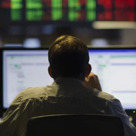 A man looking at stocks on computer screens, deciding between Risk tolerance vs risk aversion