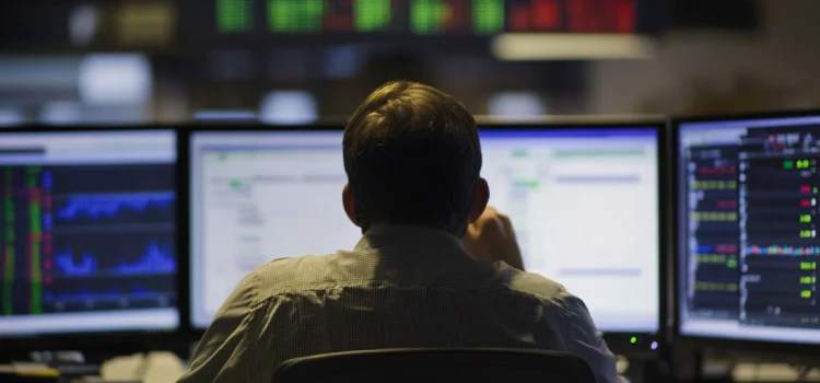 A man looking at stocks on computer screens, deciding between Risk tolerance vs risk aversion