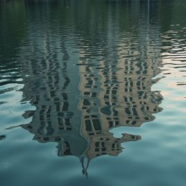 A distorted reflection of a building in a rippling lake illustrates faulty perception and memory of reality