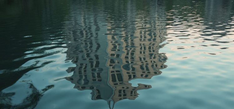 A distorted reflection of a building in a rippling lake illustrates faulty perception and memory of reality