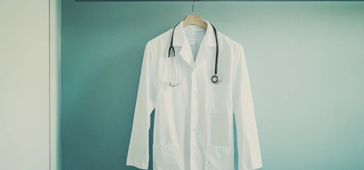 A doctor's white coat hanging on a rack