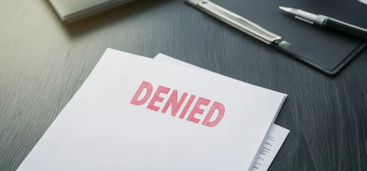 A document on a table that has the word "denied" stamped on it in red, referencing the bad healthcare in the US