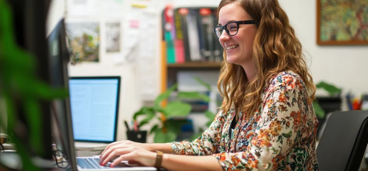 A female employee happily working at her desk, showing her flexibility and adaptability in the workplace