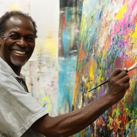 A happy man painting on a canvas in an art studio who is following his desires