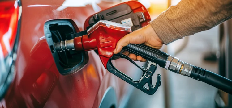 A hand pumping gas into a car at a gas station to signify the increasing gas prices