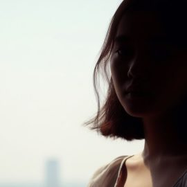 A sad woman mostly in silhouette in front of a bright window illustrates different models of grief