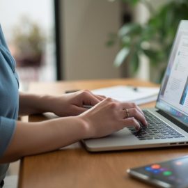 A woman typing on a laptop computer illustrates a USAJOBS application online