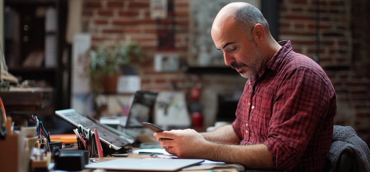A man texting on his phone at work, showing that distractions are good sometimes