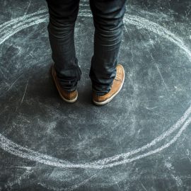 Feet standing in a drawn chalk circle on the ground, promoting expanding your creative zone