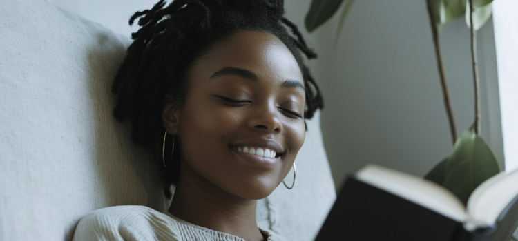 A smiling woman with eyes closed holding an open book